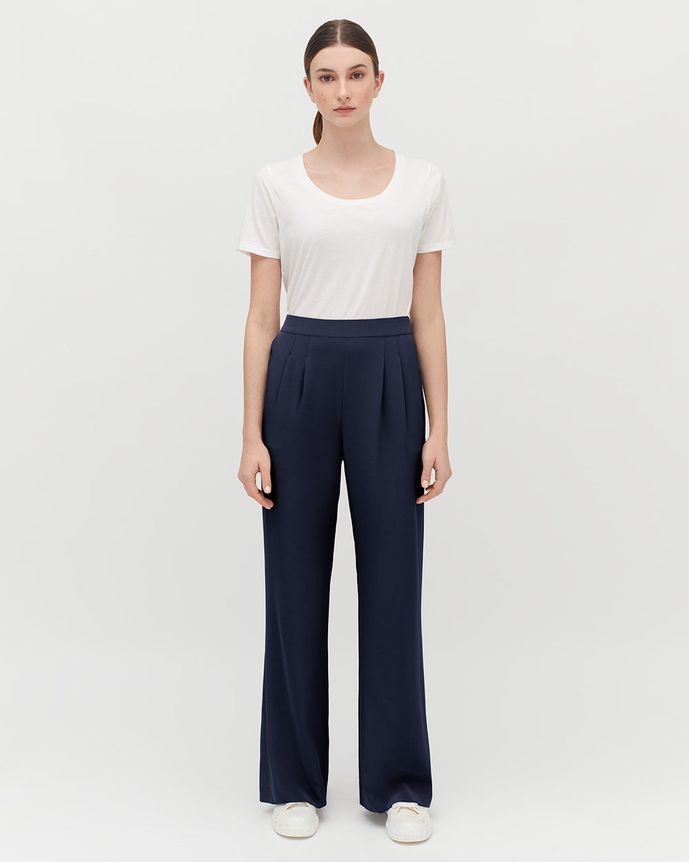 Woman standing in a t-shirt and trousers with hands at her sides