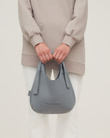 Person holding a handbag in front of them.