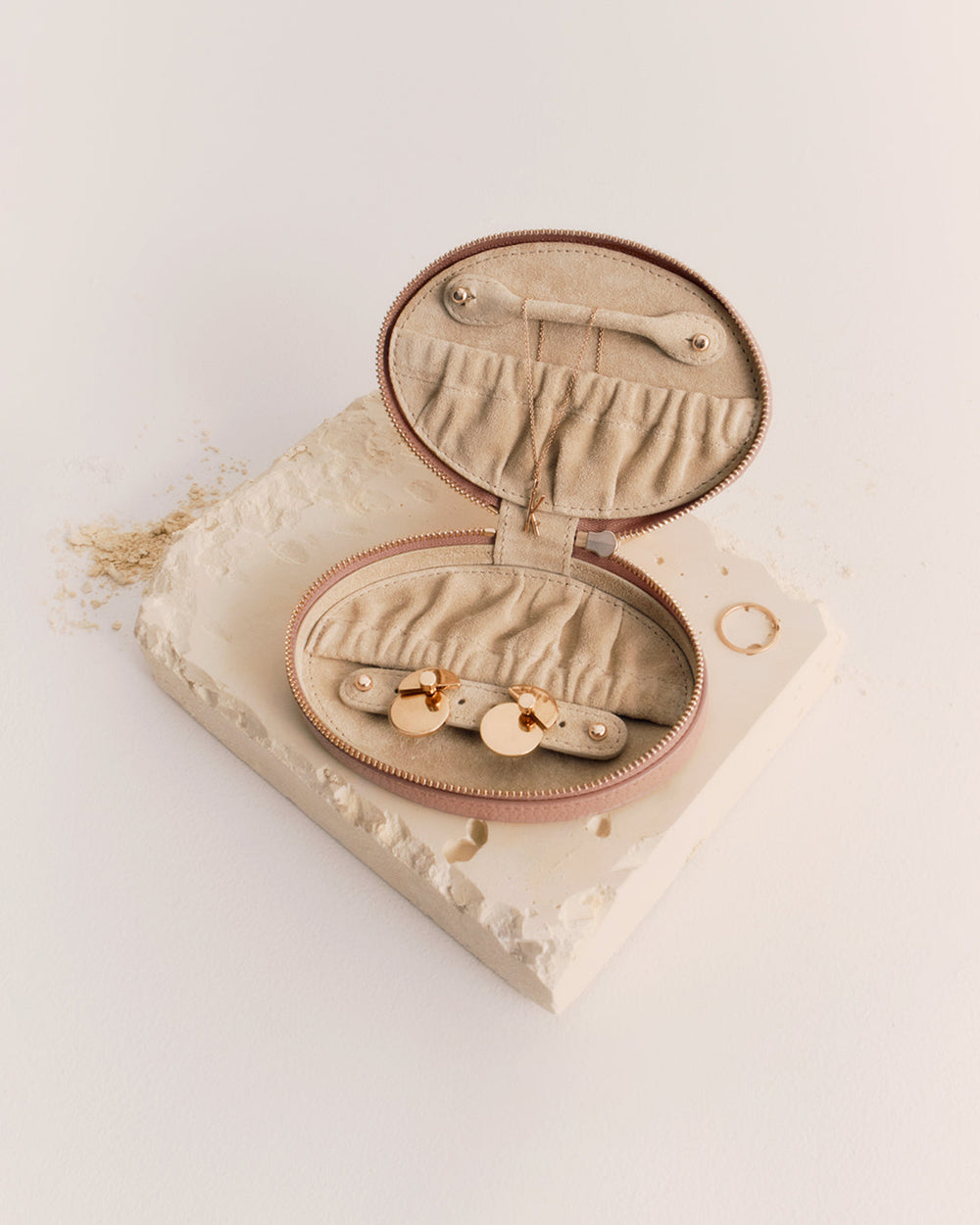 Oval jewelry case with open zipper displaying compartments inside.