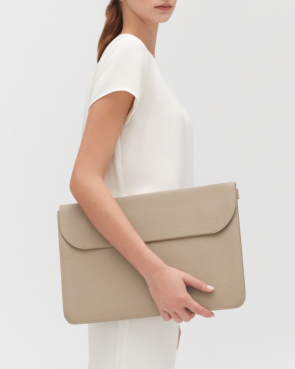 Person holding a large leather laptop sleeve