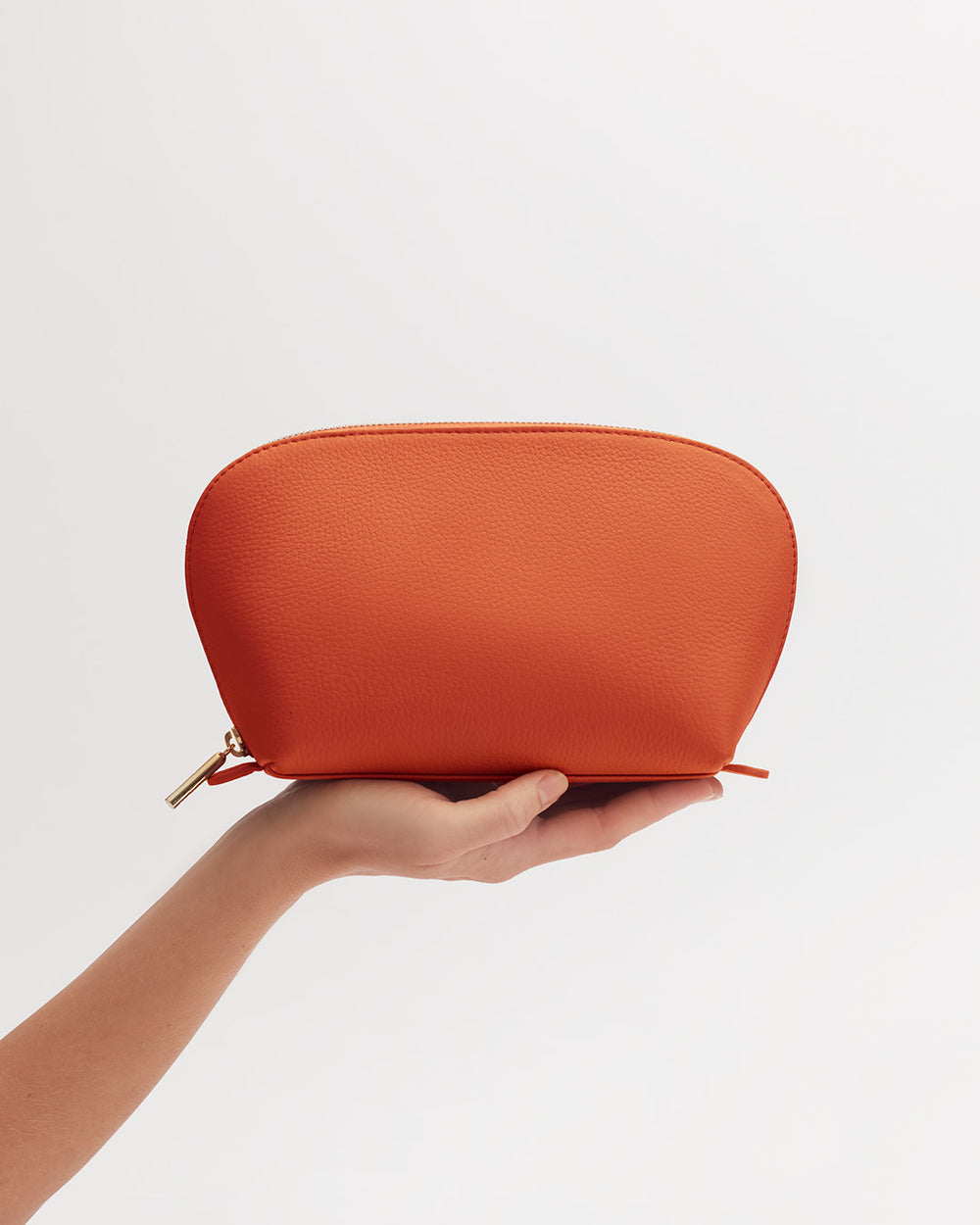 Hand holding a small zipper pouch against a plain background.