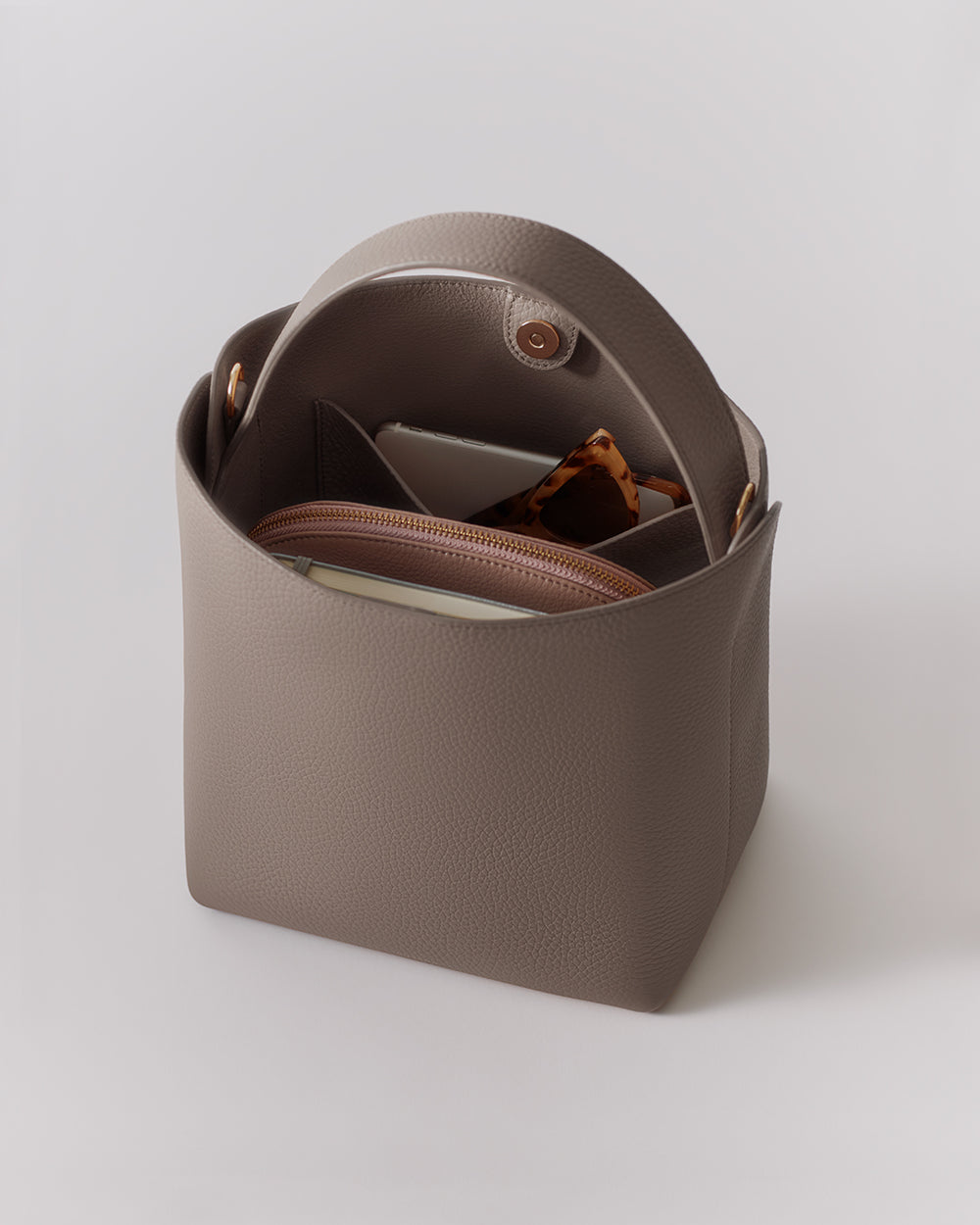 Open handbag with items inside, including a wallet and sunglasses.