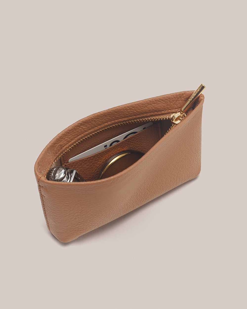 Open pouch with zipper, containing a card, perfume and a compact mirror.