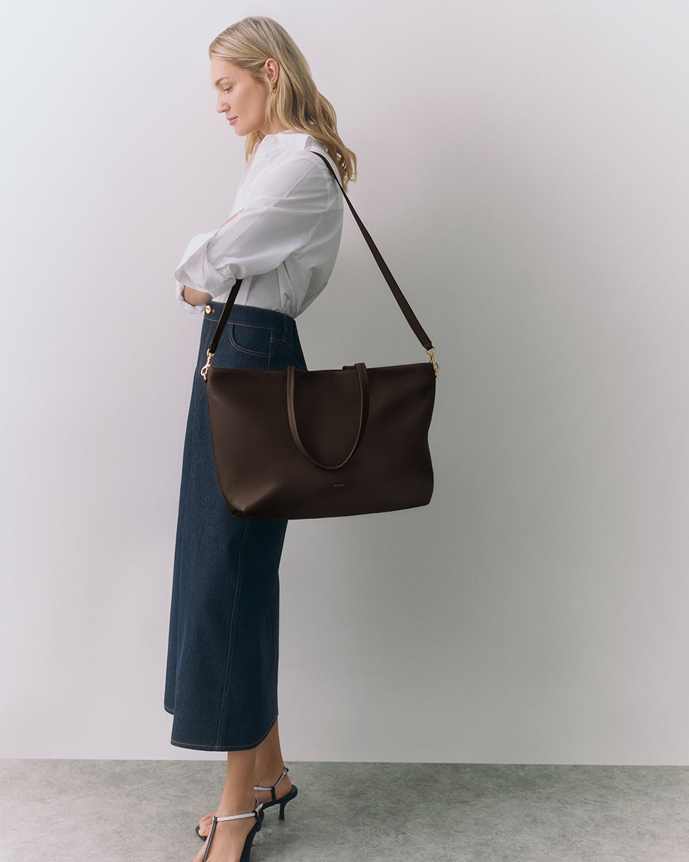 Person with shoulder bag wearing long skirt and heels