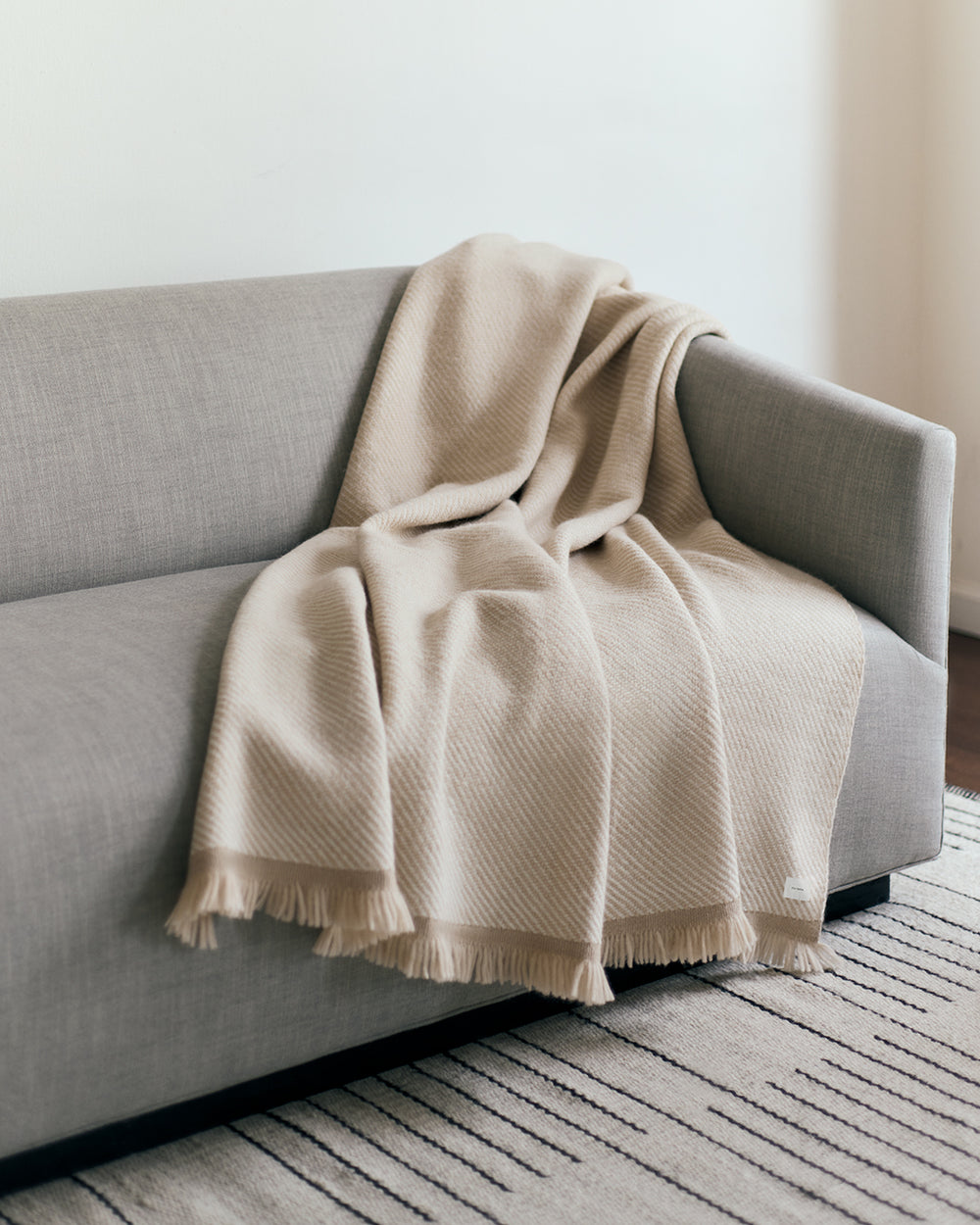 Sofa with a blanket draped over the back and side.
