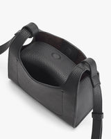 Open handbag with strap and button closure seen from above.