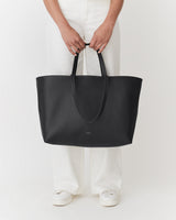 Person holding a large tote bag while standing.