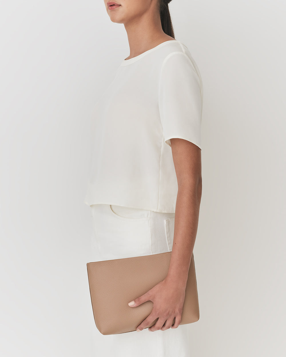 Person holding a clutch, wearing a short-sleeved top and pants