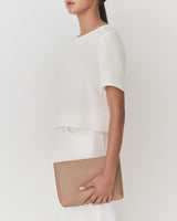 Person holding a clutch, wearing a short-sleeved top and pants