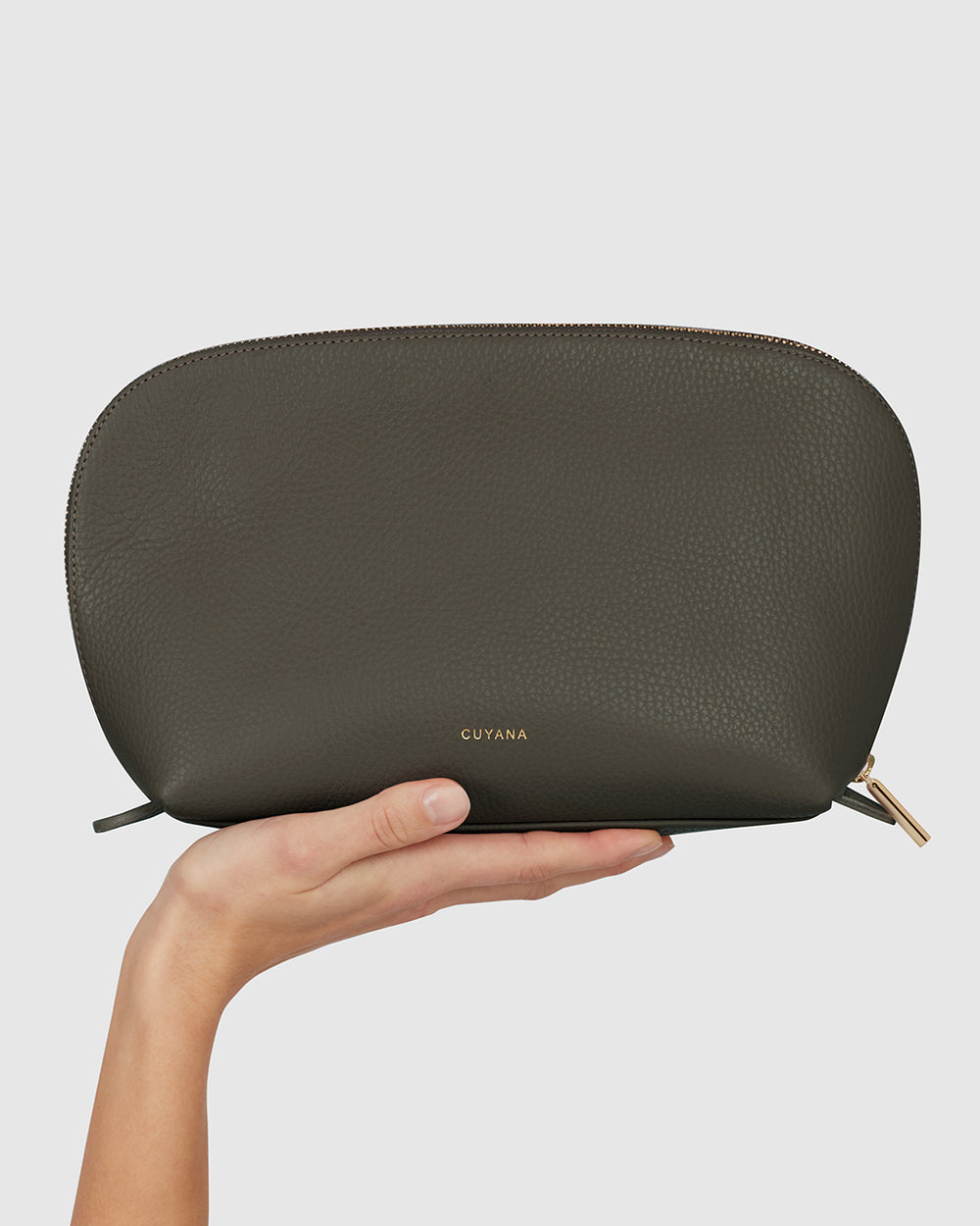Hand holding a small zippered pouch with a brand logo