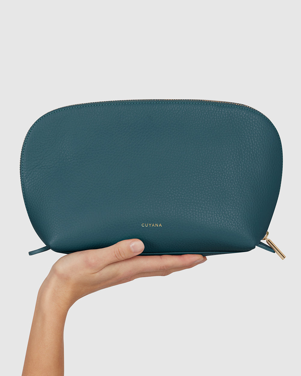 Hand holding a zipped pouch with brand name embossed
