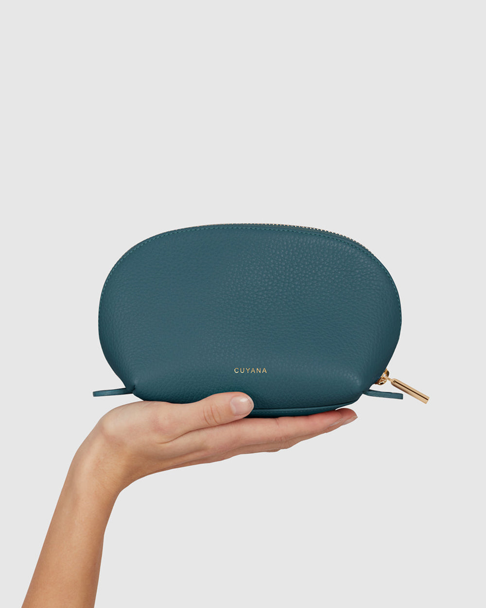 Hand holding a small zippered case with brand name.