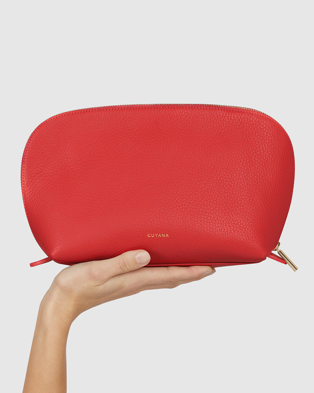 Hand holding a textured pouch with zipper and brand name embossed