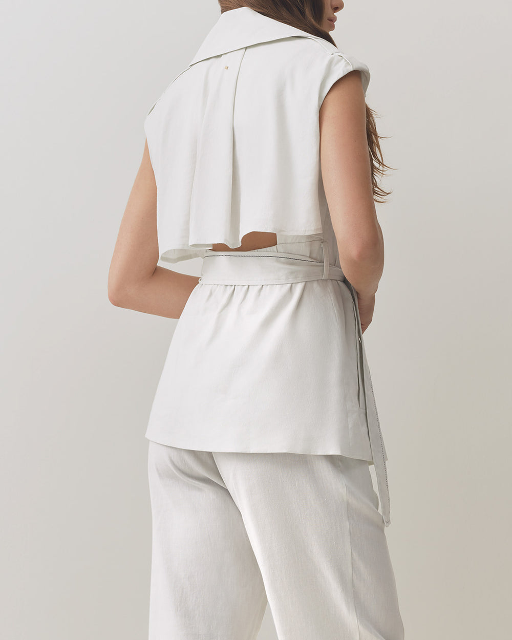Woman seen from behind wearing a sleeveless top and pants.