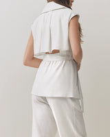 Woman seen from behind wearing a sleeveless top and pants.