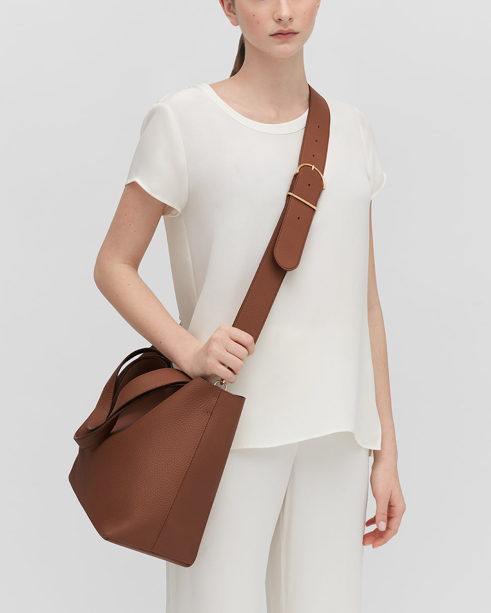 Person wearing a large handbag with a wide shoulder strap.