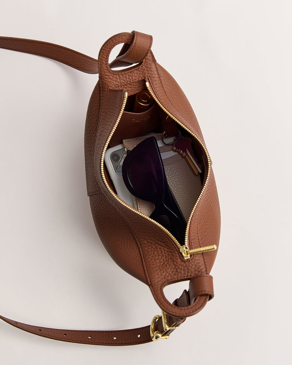 Open bag with sunglasses, phone, and keys visible inside.