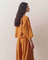 Person in loose top and wide-leg pants, looking sideways