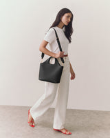 Person walking with a handbag on their shoulder, wearing a tee and pants