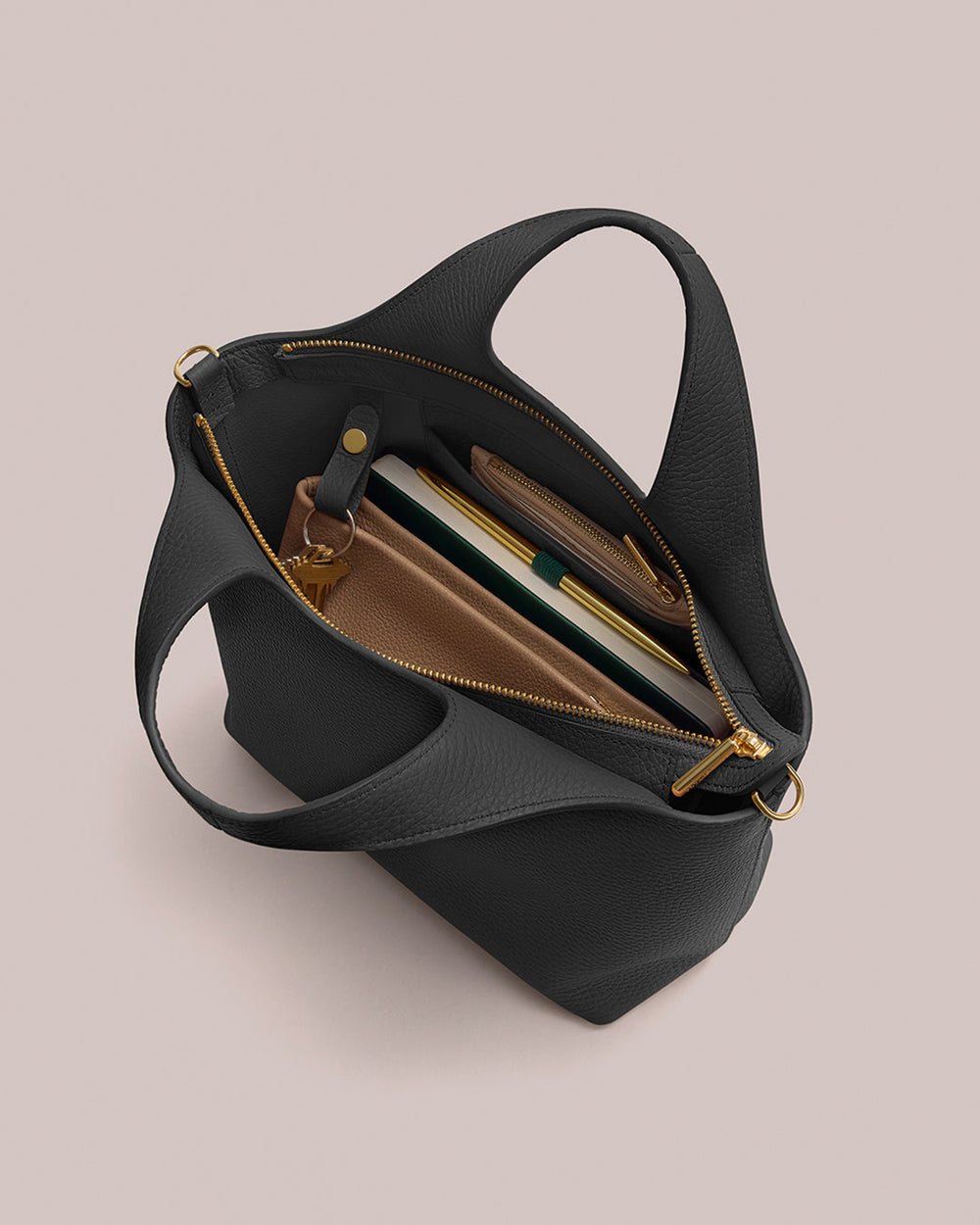 Open handbag with visible contents including a book, wallet, and pen.