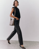 Person walking with handbag wearing sleeveless top and pants.