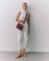Person poses with a small handbag and is wearing casual attire and sandals.
