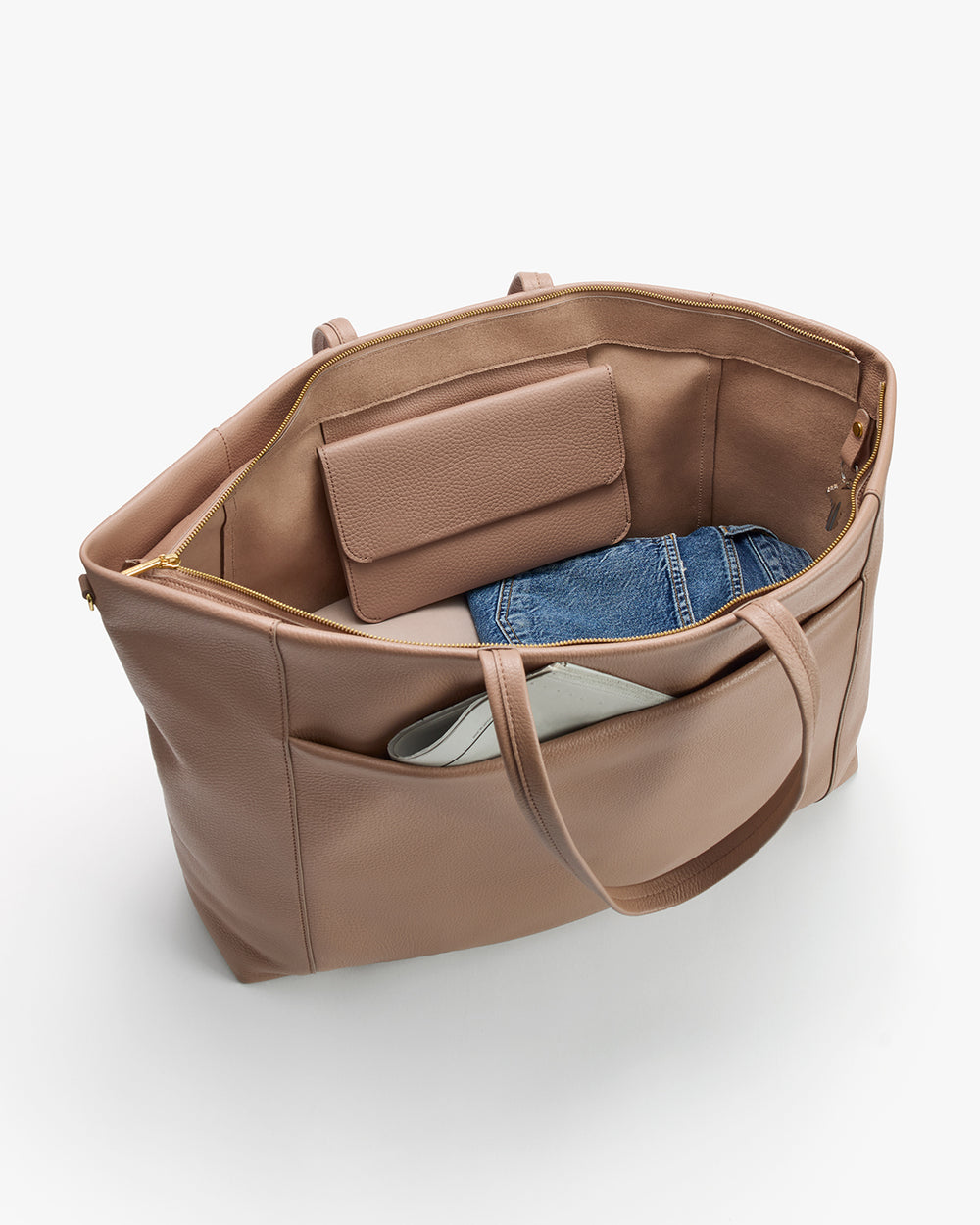 Open tote bag with wallet, jeans, and book inside and pocket.