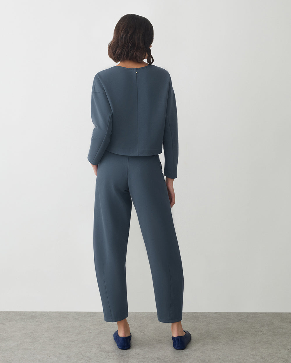 Person wearing a matching top and pants, standing with back facing the camera.
