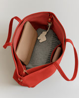 Open travel bag with wallet, keychain, and folded fabric inside.