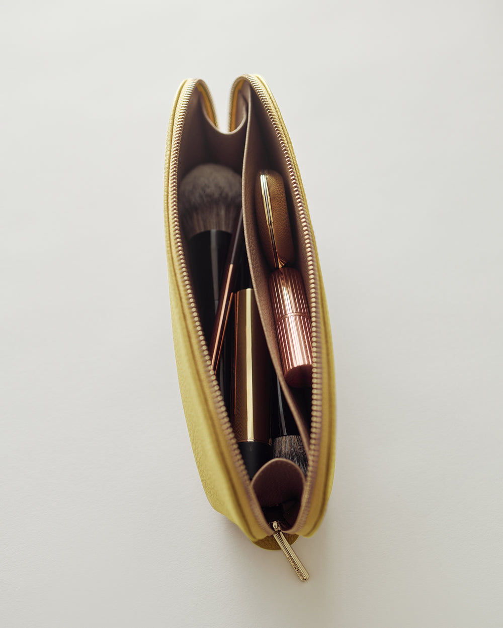 Makeup bag with brushes and lipstick inside.