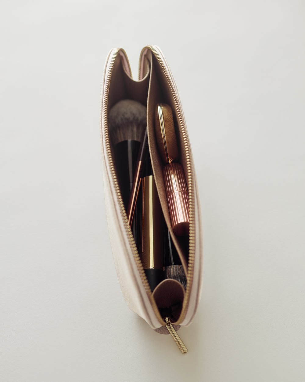 Cosmetic bag with makeup brushes and lipstick inside.