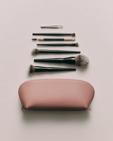 Makeup brushes and tools arranged above a cosmetic bag.