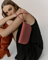 Person sitting in dress holding purse, wearing high boots.