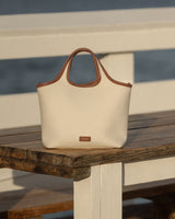 A handbag with handles on a wooden table outdoors.
