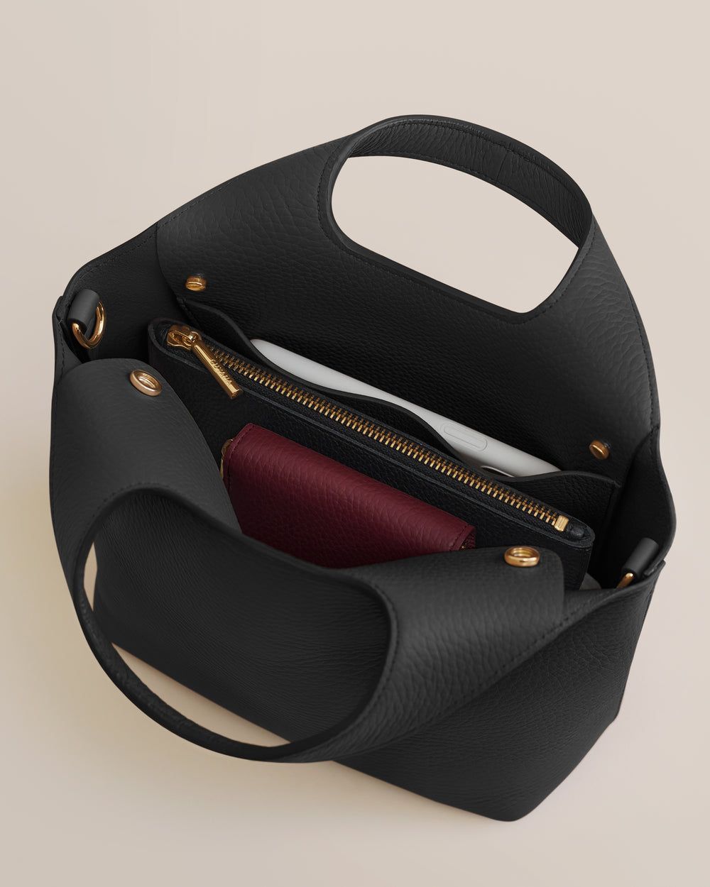 Open handbag with a zipper pocket and a red wallet inside.