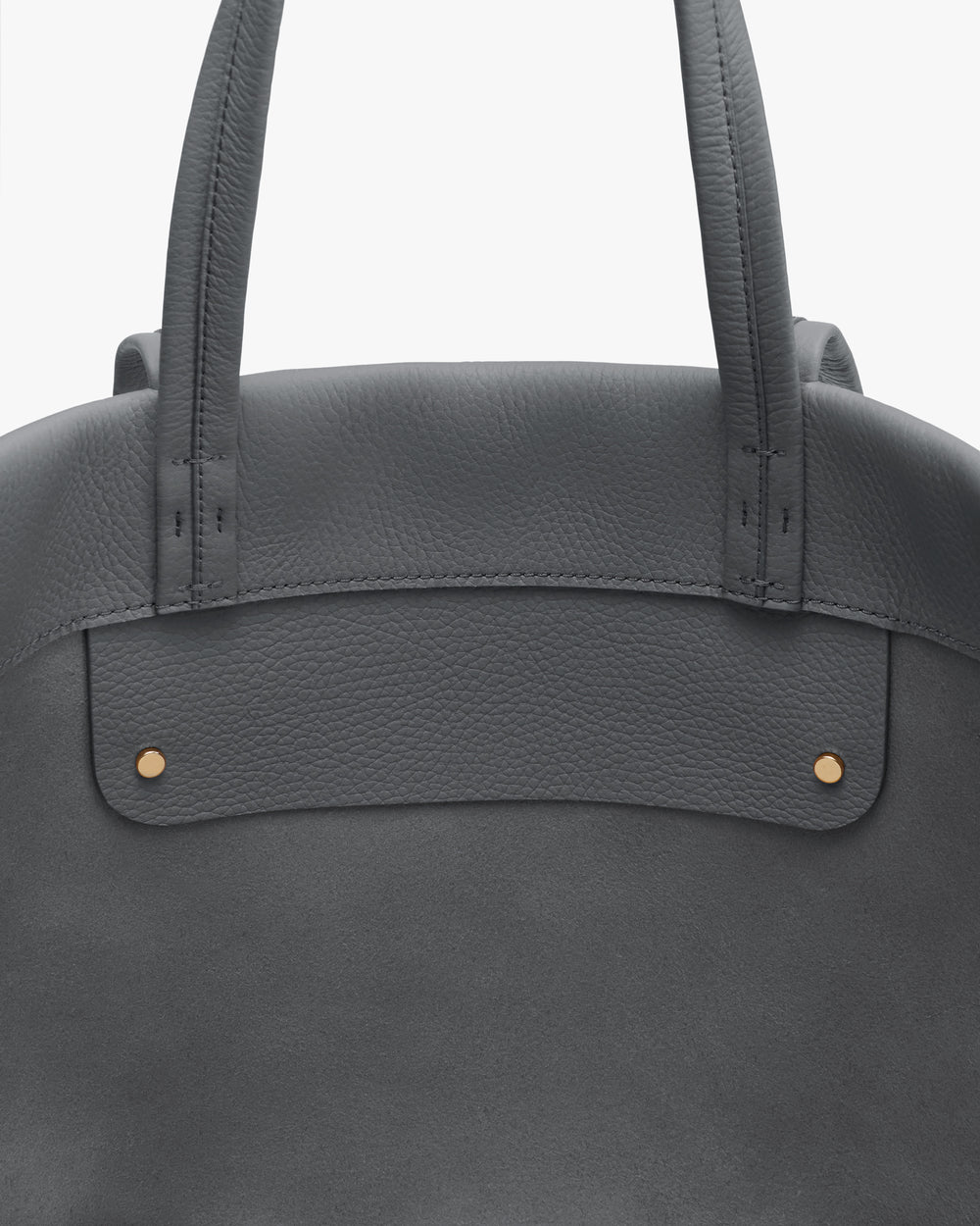 Close-up of a tote bag with two handles and gold stud details.