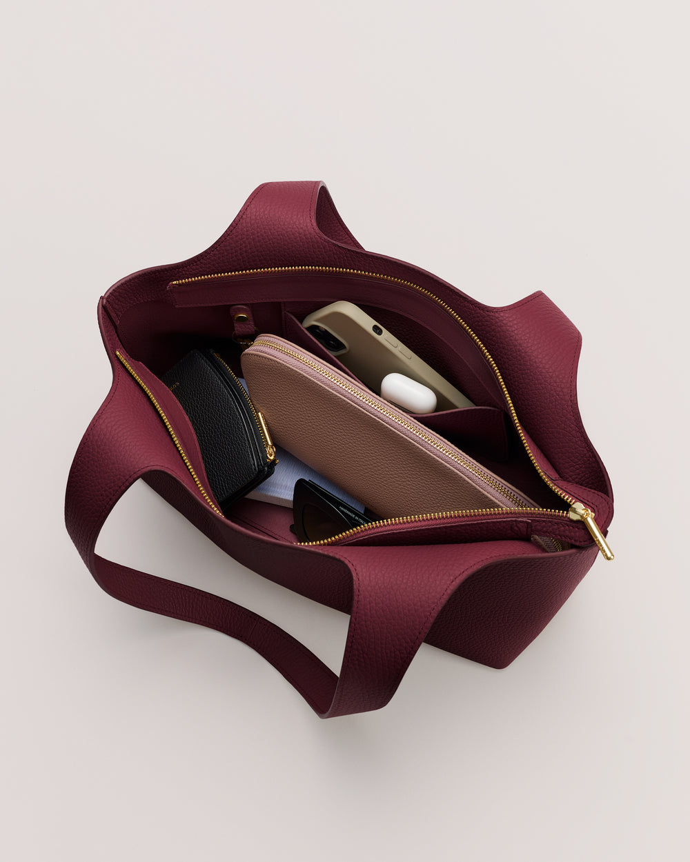 Open handbag with wallet, phone, earbuds, and small pouch inside