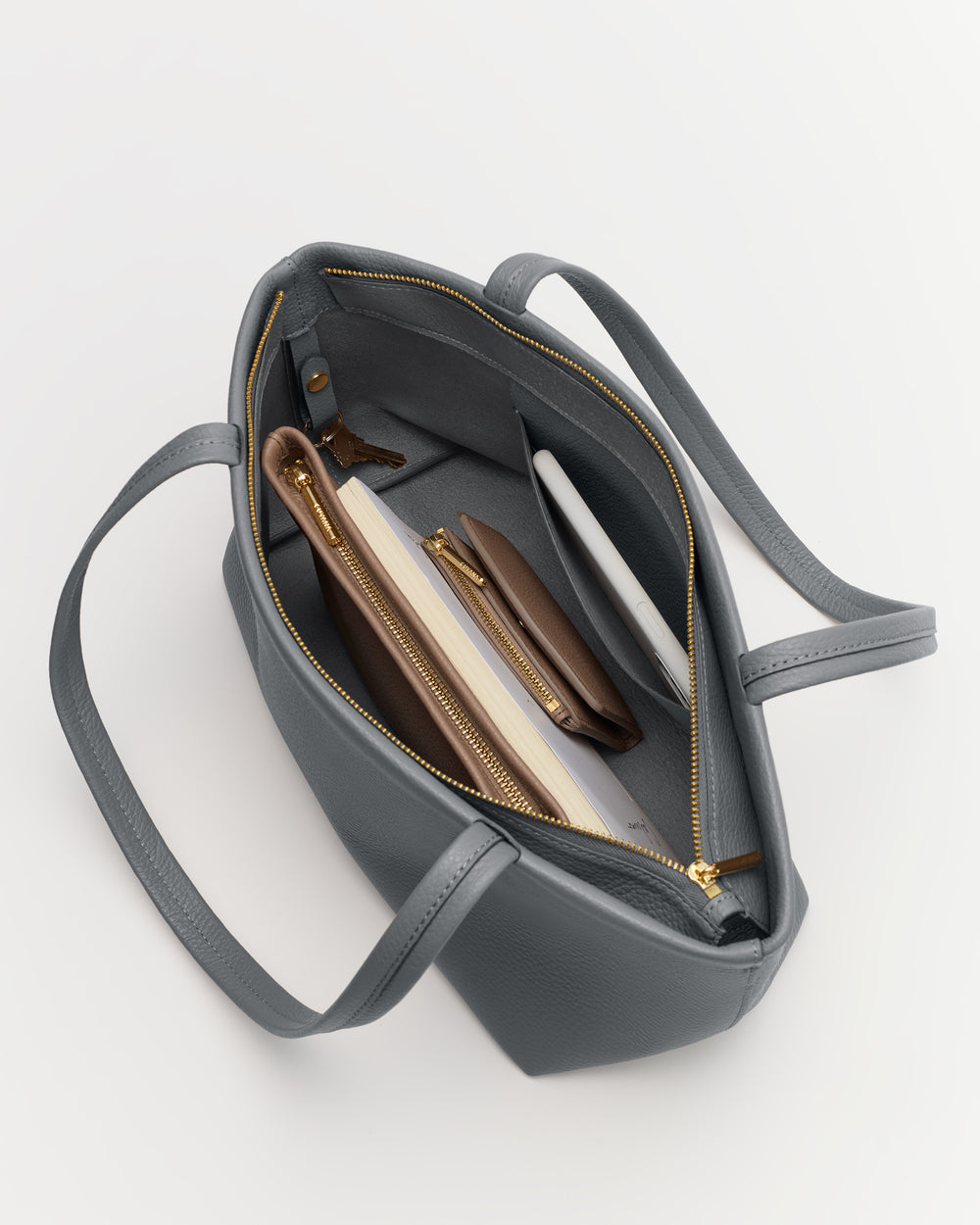 Open handbag with visible items inside, including wallet, notebook, and pen.