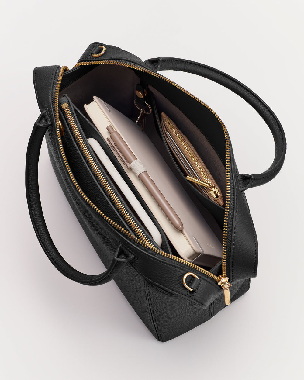 Open handbag with visible contents like a notebook, pen, and a zippered pouch.