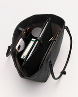 Open handbag with notebook, tablet, phone, bottle, and other items inside.