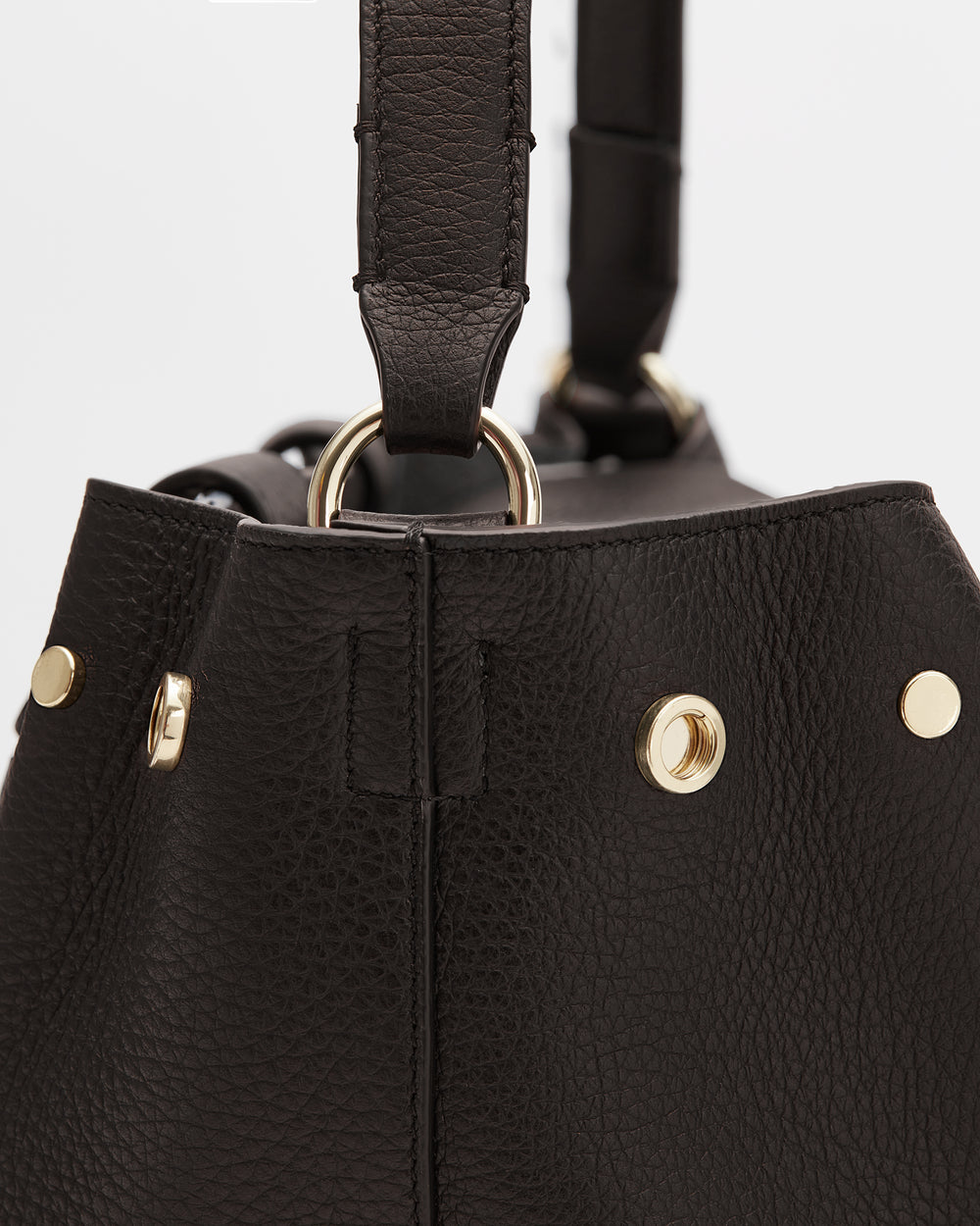 Close-up of a textured handbag with metal rings and studs.