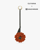 Floral keychain with a round loop and the words Cuyana and Gold House visible.