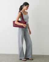 Person in sleeveless top and jeans holding a shoulder bag