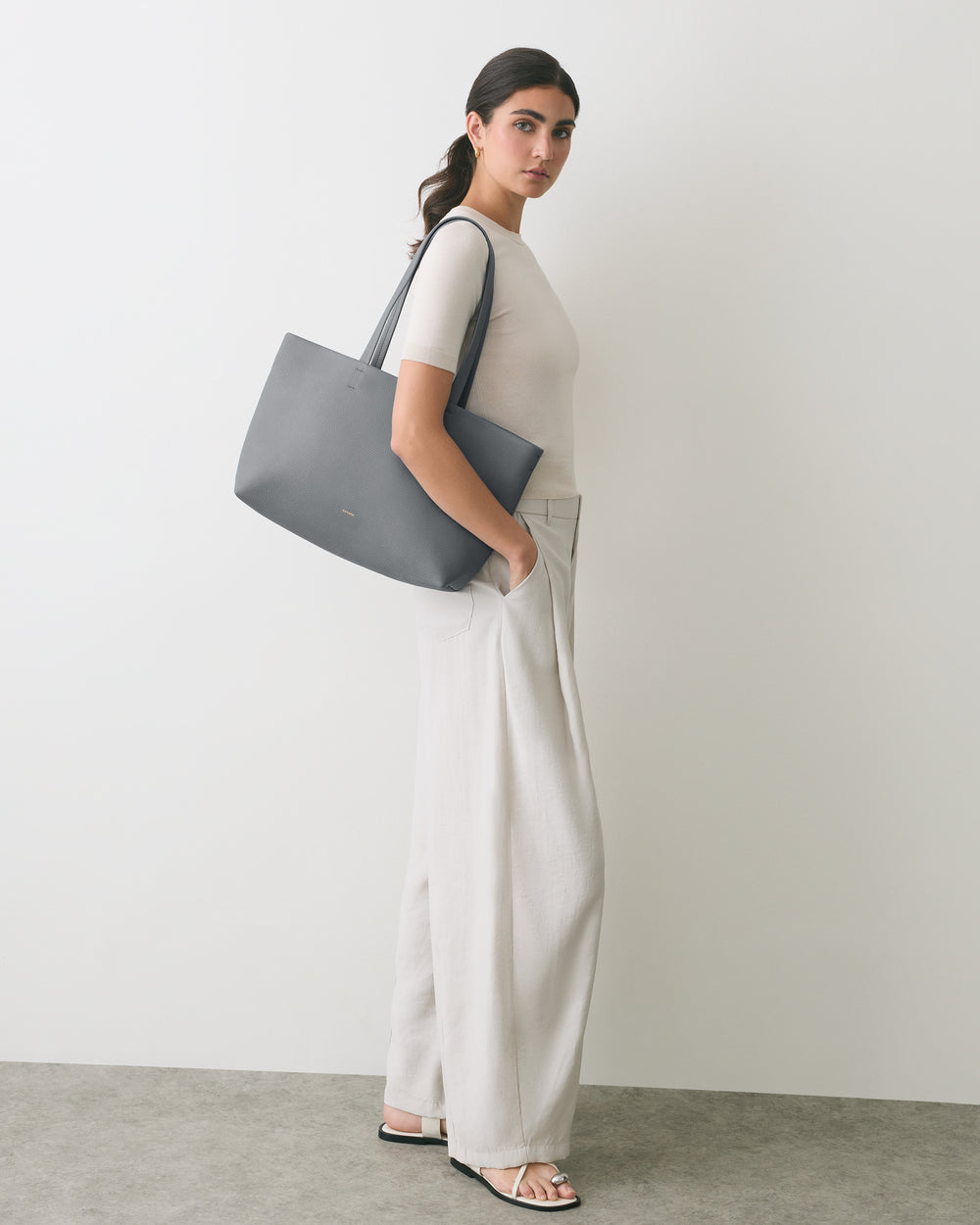 Person standing with large shoulder bag and wide-leg pants