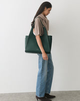 Person standing with large handbag, wearing jeans and boots