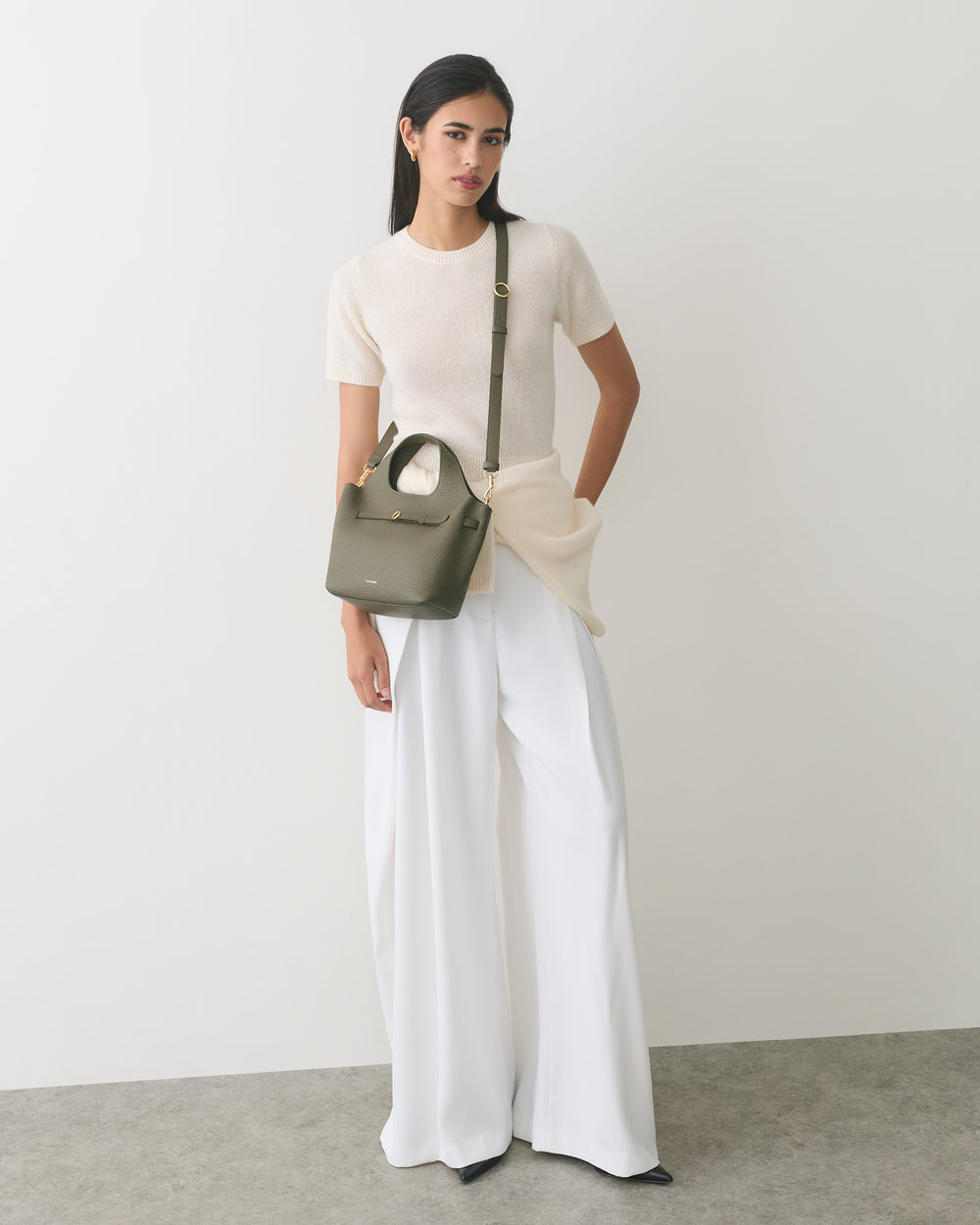 Person wearing a short-sleeve top and wide-leg pants, holding a small shoulder bag.