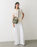 Person wearing a short-sleeve top and wide-leg pants, holding a small shoulder bag.