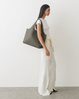 A person carrying a large bag wearing a top and loose pants.