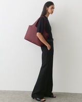 Person standing with large shoulder bag wearing sandals and wide-leg pants.