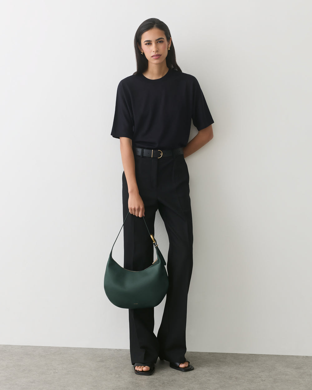 Person wearing a shirt and pants, holding a bag in one hand.